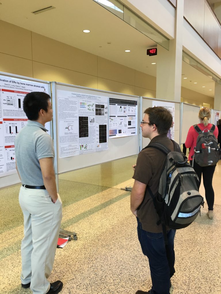 Two students talking in front of poster